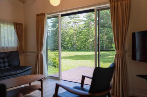 a living room with a large sliding glass door at アルプスシャレー in Hokuto
