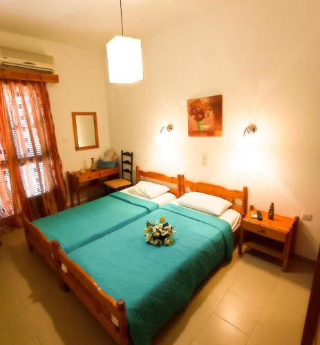 a bedroom with a large bed with a blue blanket at PANSION KONSTANTINOS in Skiathos