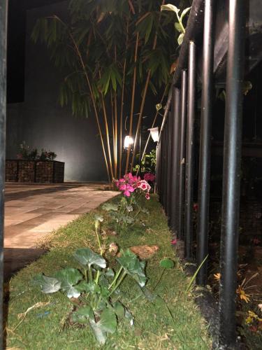 a fence with pink flowers and plants next to a sidewalk at 3 Arch Resort Ella in Ella