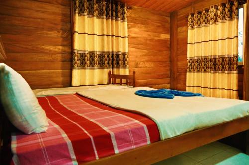 1 dormitorio con 1 cama con paredes de madera en Discovery resort, en Ratnapura