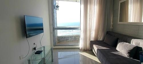 uma sala de estar com um sofá e uma grande janela em Apart Hotel TLV/Bat Yam Beach Front 1207 em Bat Yam