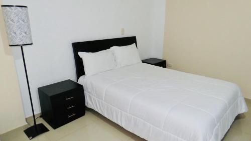a bedroom with a white bed and a lamp at Mirador de San Jorge in Girardot
