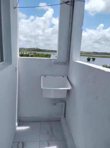 a white bathroom with a sink and a window at Flats Elohim in Porto De Galinhas