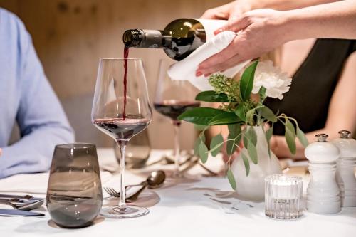 a person pouring wine into a wine glass on a table at Hotel Weisses Lamm in See
