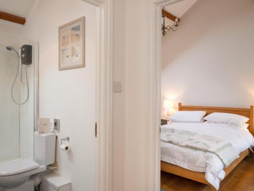a white bedroom with a bed and a toilet at Woodpeckers Barns in Liskeard