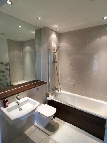 a bathroom with a sink and a toilet and a bath tub at Modern 2 Bedroom Penthouse with Balcony & Parking in London