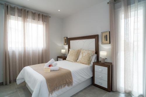 1 dormitorio con 1 cama con sábanas y almohadas blancas en AAC Málaga - Apartamento con terraza, muy amplio, totalmente equipado, cerca del centro y nuevo! en Málaga