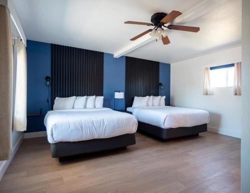 two beds in a room with blue walls and a ceiling fan at Balanced Rock Inn in Fruita