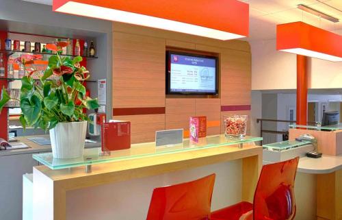 a restaurant with a counter with a potted plant at Ibis Roscoff in Roscoff
