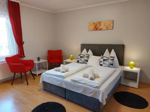 a bedroom with a large bed and two red chairs at Barbara Wellness Pension in Keszthely