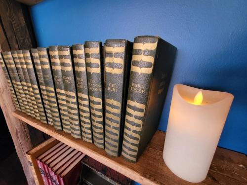 a row of books sitting on a shelf next to a candle at L'Entre 2 Cols in Saint-Martin-sur-le-Chambre