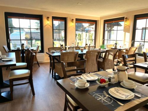 - une salle à manger avec des tables, des chaises et des fenêtres dans l'établissement Pension Windrose, à Prerow