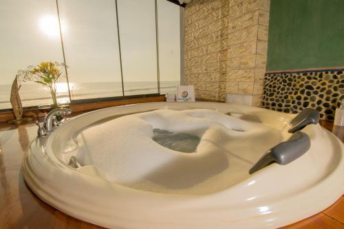 a large white bath tub in a bathroom at Hotel Huankarute in Huanchaco