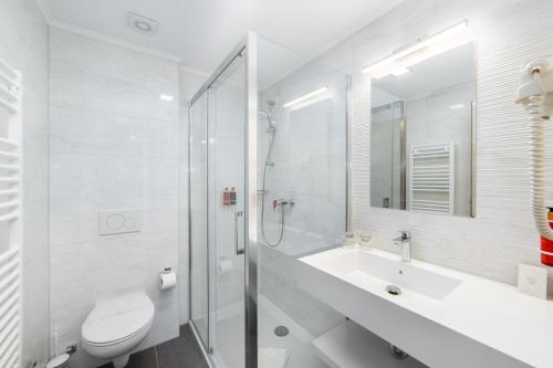 a white bathroom with a toilet and a sink at Hotel Bella Vista in Drvenik