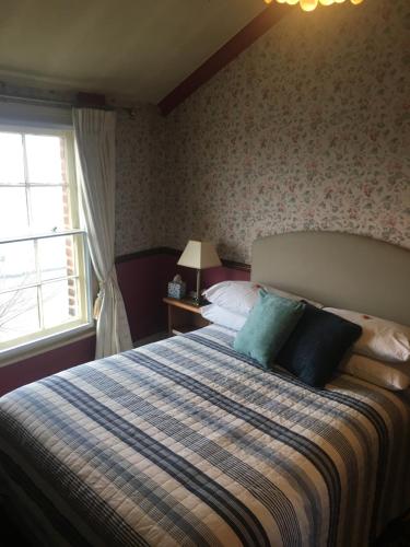 a bedroom with a bed with blue pillows and a window at Regency House in Walton-on-the-Naze