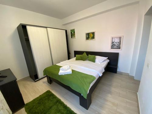 ein Schlafzimmer mit einem großen Bett und einer grünen Decke in der Unterkunft Apartament Ella T2 in Mamaia Nord – Năvodari