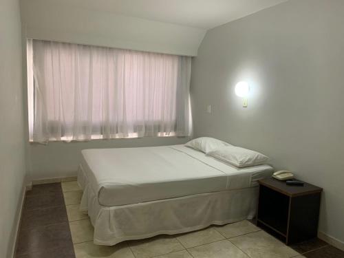 a small bedroom with a bed and a window at Hotel Doral Apucarana in Apucarana