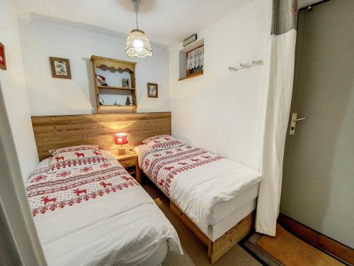2 Betten in einem kleinen Zimmer mit Spiegel in der Unterkunft Studio PRAZ SUR ARLY in Praz-sur-Arly
