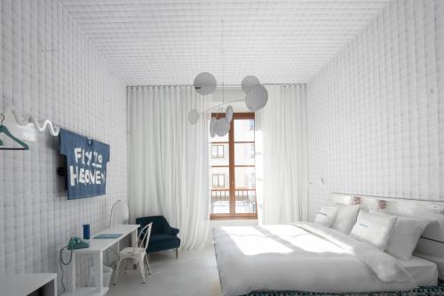 a white bedroom with a large bed and a desk at 25hours Hotel Florence Piazza San Paolino in Florence
