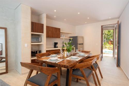 a kitchen and dining room with a wooden table and chairs at Suites at TreeTops Tulum in Tulum