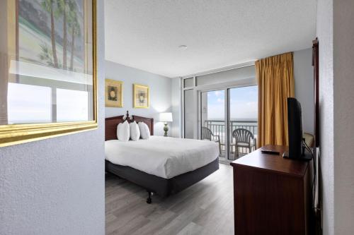 ein Hotelzimmer mit einem Bett und einem Balkon in der Unterkunft Hosteeva Newly Renovated Ocean Front Spacious Condo in Atlantica Resort in Myrtle Beach