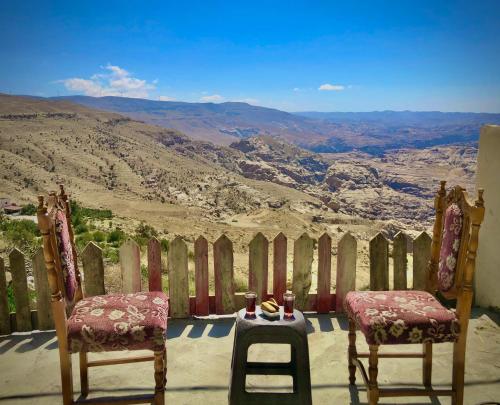 2 sedie e un tavolo con vista sulle montagne di Petra NefNaf Hostel a Wadi Musa