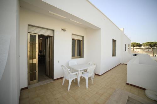 ein weißes Esszimmer mit Tisch und Stühlen in der Unterkunft Appartamenti Mancaversa in Marina di Mancaversa