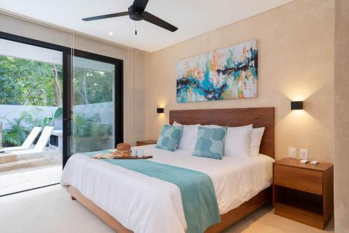 a bedroom with a large bed with a ceiling fan at Suites at TreeTops Tulum in Tulum
