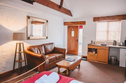 a living room with a leather couch and a table at Home Farm & Lodge in Bawtry