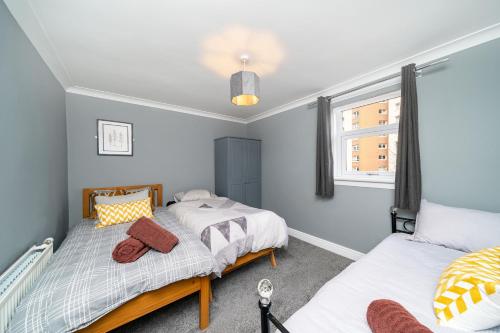 2 camas individuales en una habitación con ventana en Dalmarnock Stay en Glasgow