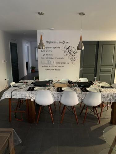 - une table avec des chaises blanches et un panneau dans la chambre dans l'établissement Les Chalets Baie Cascouia, Nature & Expérience, à Larouche