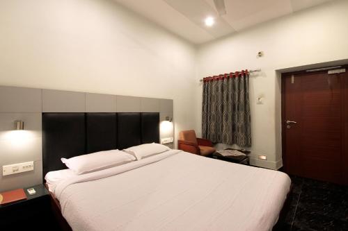 a bedroom with a large white bed and a chair at Taj Mahal Hotel Abids in Hyderabad