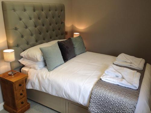 a bedroom with a bed with white sheets and blue pillows at Kingfisher Lodge in Froggatt