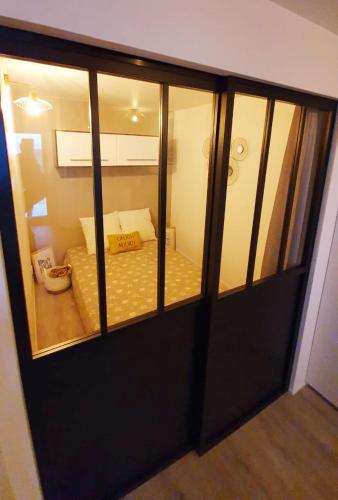 a sliding glass door with a bed in a room at Cosy T2 refait à neuf climatisé, vue mer avec terrasse et jardin, Wifi piscine tennis et parking in Sète