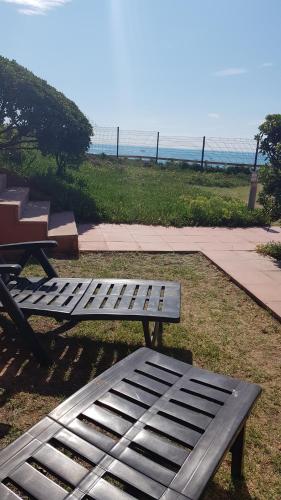 a bench sitting in the grass next to a picnic table at Cosy T2 refait à neuf climatisé, vue mer avec terrasse et jardin, Wifi piscine tennis et parking in Sète