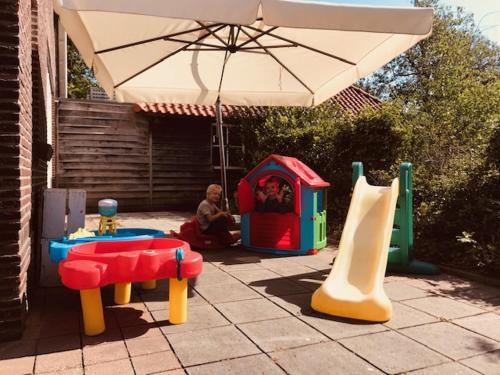 a child sitting under an umbrella next to a playground at Glamping in Nature by Outdoors in Holten