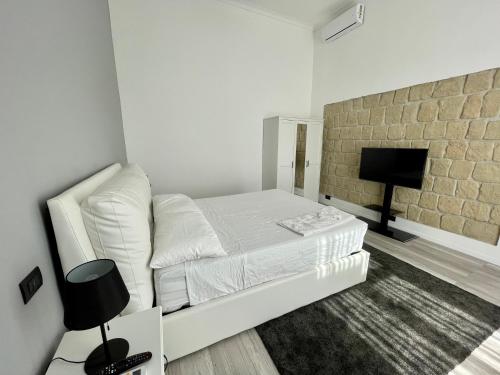 um quarto branco com uma cama e uma televisão de ecrã plano em Napoli Comfort Home em Nápoles