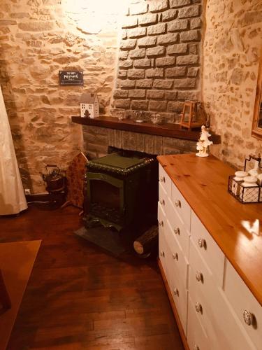 - une cuisine avec un poêle à bois dans un mur en briques dans l'établissement Maison Blanche De Hudson, à Cussac