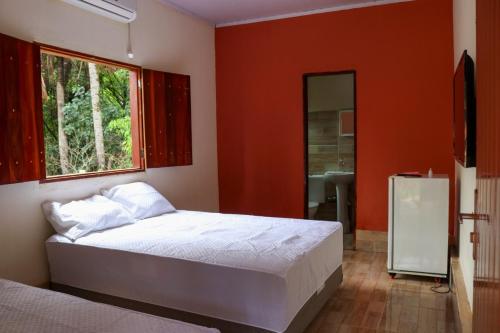 een slaapkamer met een bed, een raam en een spiegel bij CHACARA ESPERANÇA in Pirenópolis