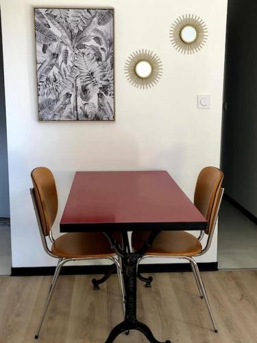 einen Tisch und Stühle in einem Zimmer mit zwei Spiegeln in der Unterkunft Sainte Cécile 4 - Studio élégant et central in Vichy