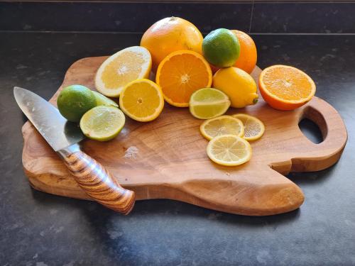 a cutting board with oranges and lemons and a knife at The Shambles by Spires Accommodation A Boho styled place to stay just 3 miles from Birches Valley visitors Centre Cannock Chase in Rugeley