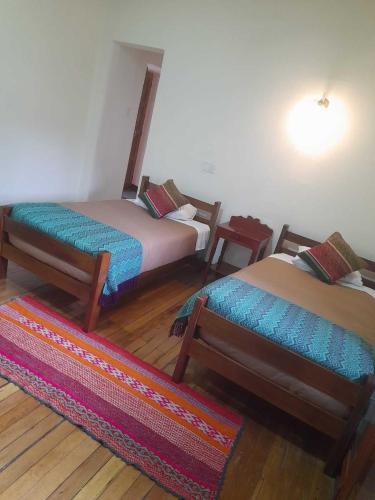 a room with two beds and a rug at Terra Sagrada Cusco in Cusco
