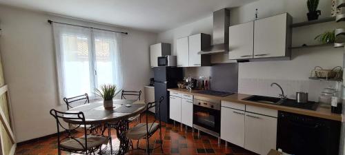 une cuisine avec une table et des chaises et une cuisine avec des armoires blanches dans l'établissement Appartement leucate, à Leucate