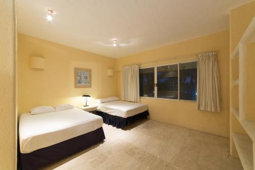 a bedroom with two beds and a window at Hotel Villamar Princesa Suites in Acapulco
