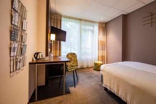 a hotel room with a bed and a desk at Buitenplaats de Bergse Bossen in Driebergen