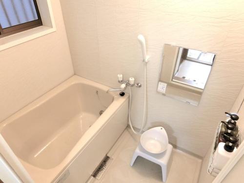 a white bathroom with a tub and a toilet at Sepia Court Inn セピアコートイン in Urayasu