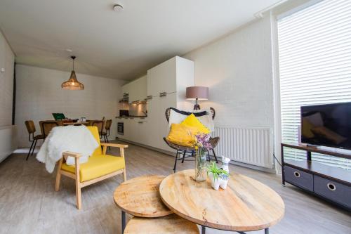 a living room with a television and a table and chairs at Buitenplaats de Bergse Bossen in Driebergen
