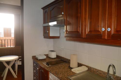 a kitchen with wooden cabinets and a counter top at Holiday House Always Sun in Playa de Santiago