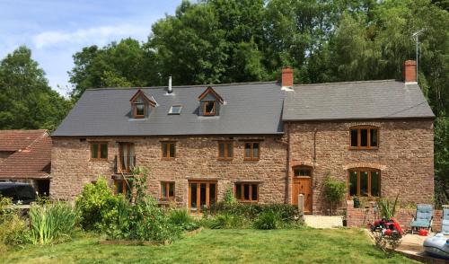 ein großes Backsteinhaus mit grauem Dach in der Unterkunft Woodmill Farm Cottage in Alvington