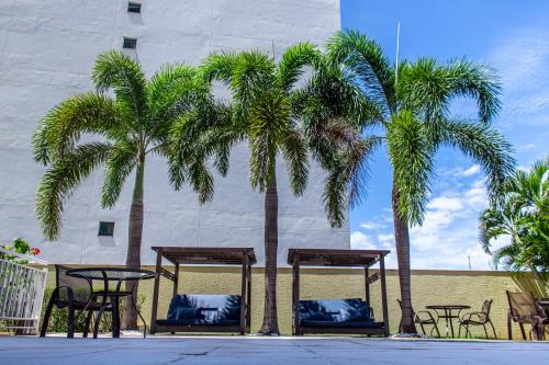 duas palmeiras com mesas e cadeiras em frente a um edifício em Delmond Hotel em Cuiabá